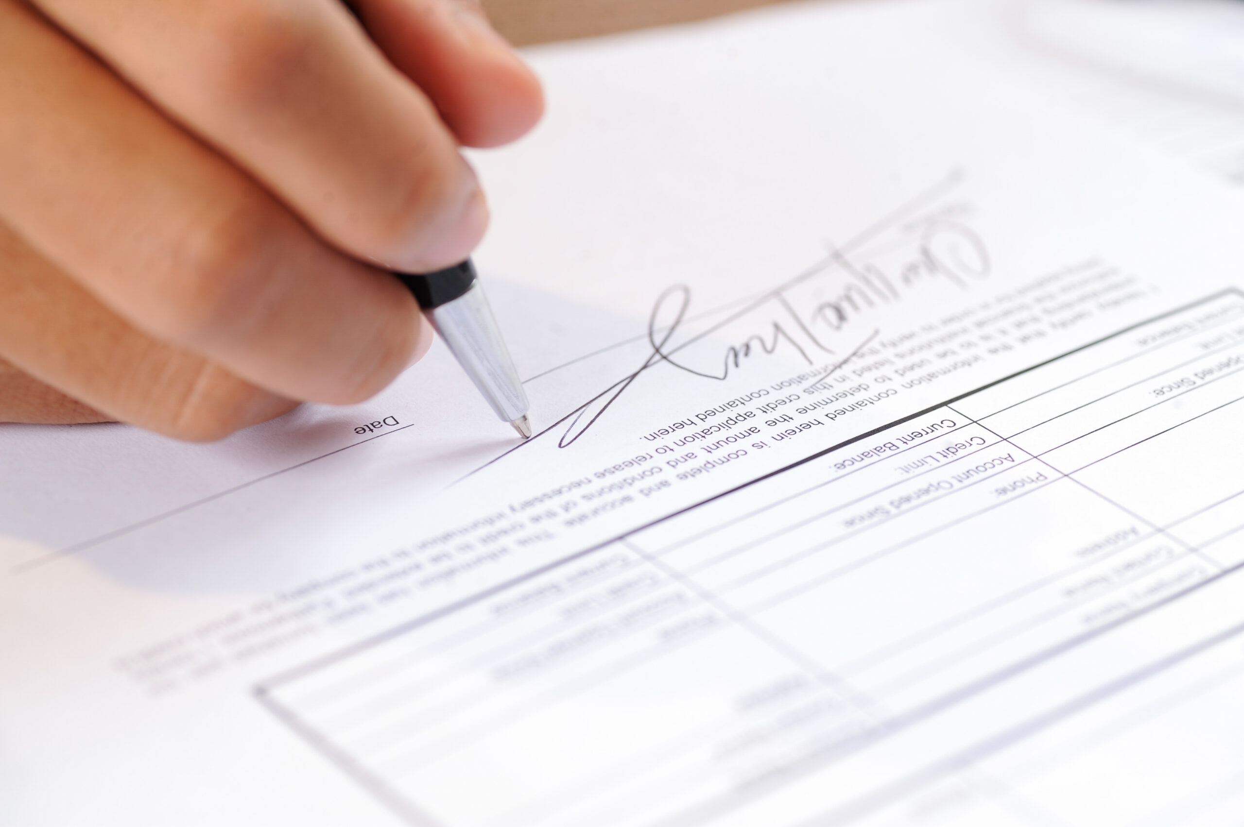 Closeup of person signing document with ball pen.